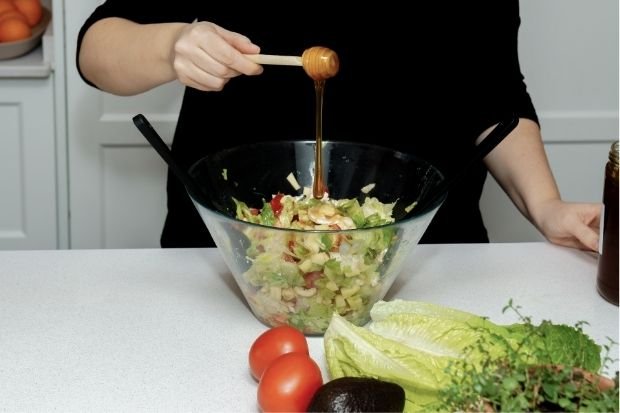 Pouring Honey Into Fresh Salad