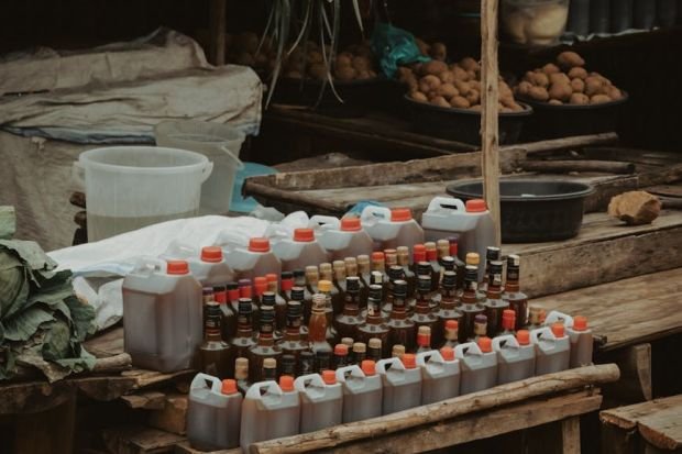Outdoor grocery stall with various bottles and fresh produce, showcasing local market ambiance.